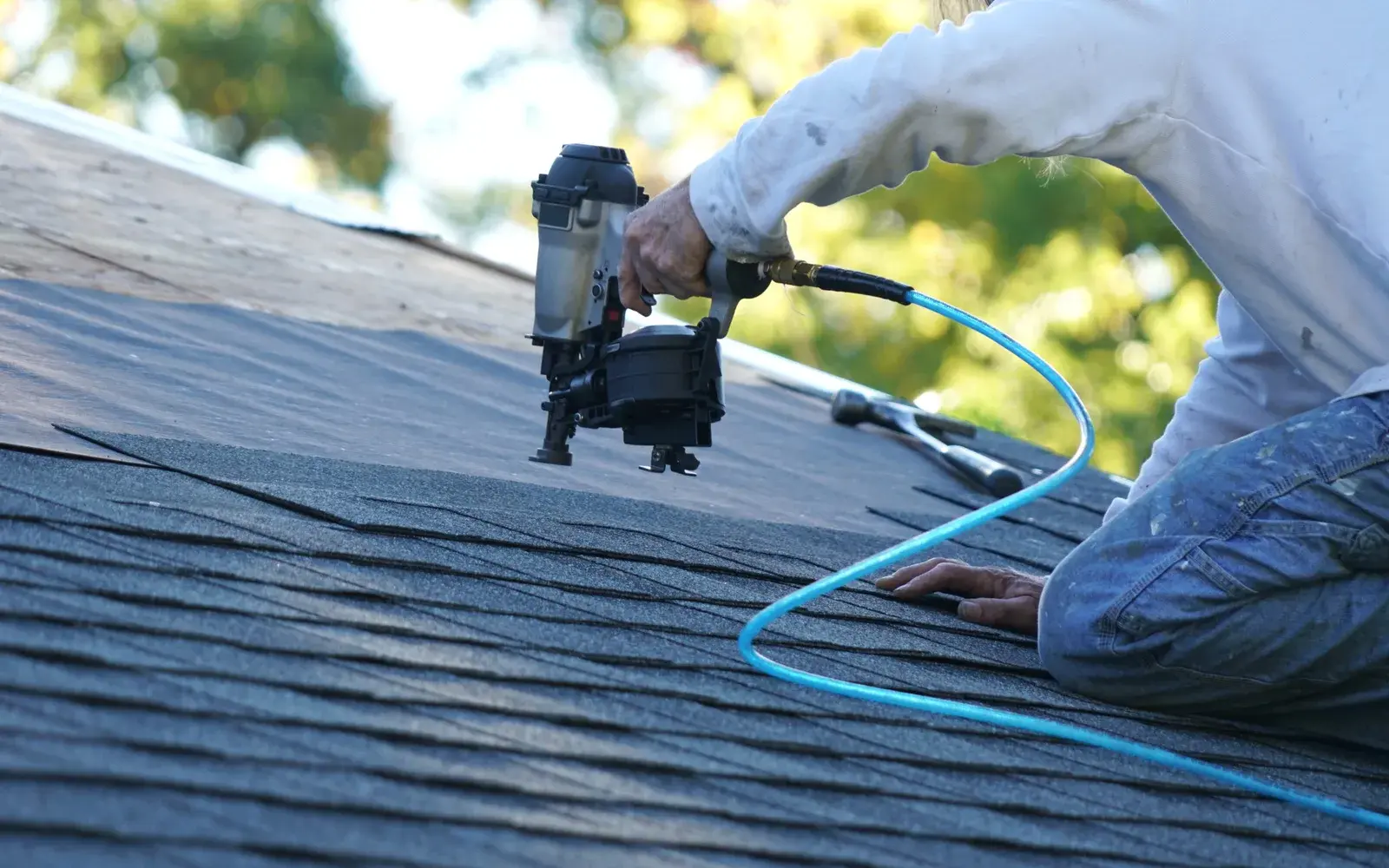 Orange Exteriors roofer fastening new asphalt shingles on a home in Eden Prairie, MN Orange Exteriors roofer fastening new asphalt shingles on a home in Eden Prairie, MN